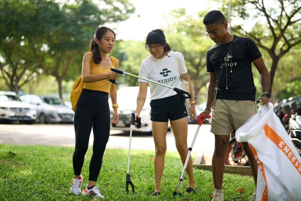 three people picking up street litter with trash pickers, with Yasser on the right