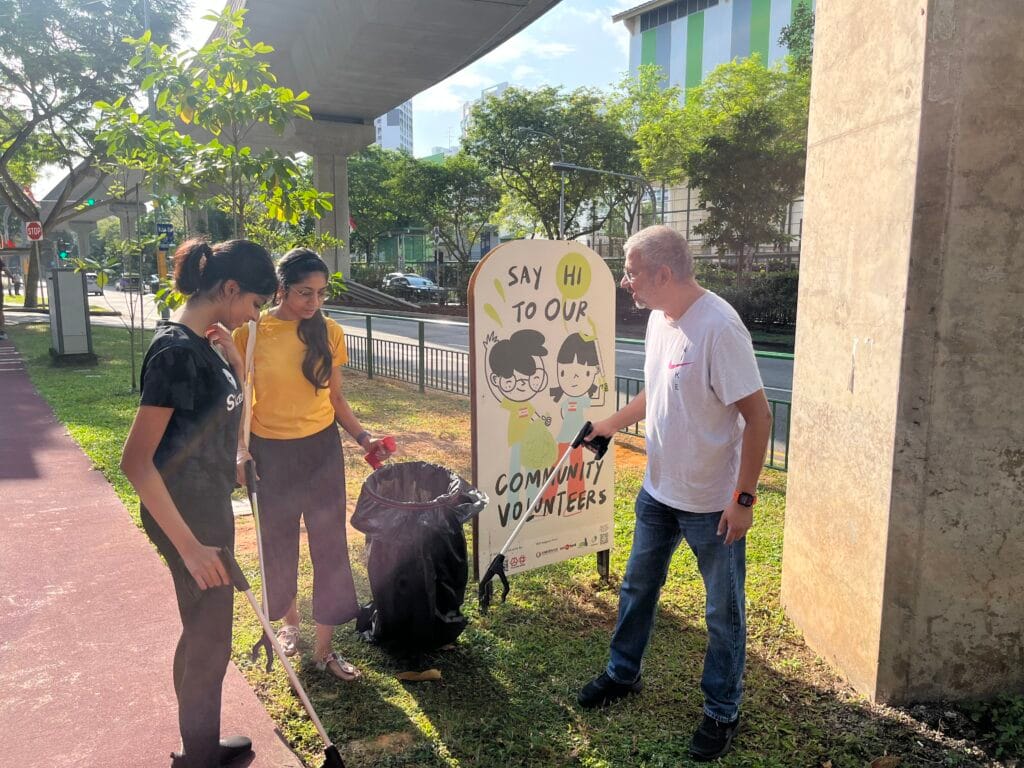 residents picking up trash in front of a community sign