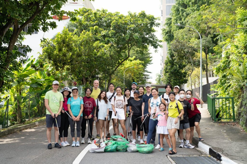 Group of people gather after a street clean-up, with trash placed in front of them